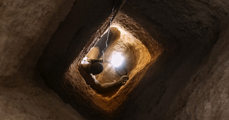 Worker in gold mine climbing down a shaft.